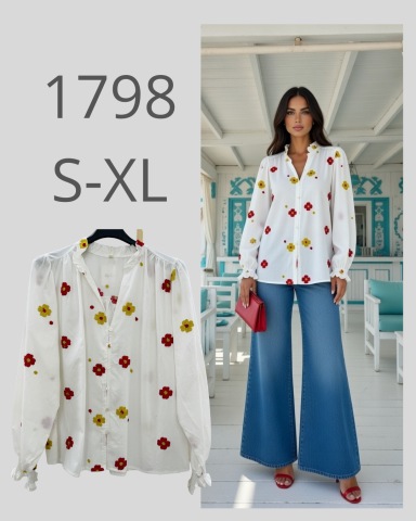 Blusa blanca con flores rojas y amarillas, modelo con pantalones anchos y bolso rojo.