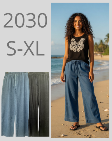 Mujer sonriendo en la playa, usando pantalones anchos y camiseta sin mangas.