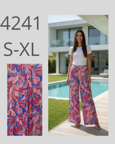 Mujer posando con pantalones amplios de estampado colorido frente a una casa moderna.