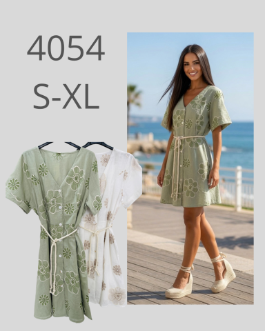 Mujer sonriente usando un vestido verde con estampado, de pie junto a la playa.