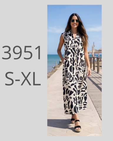Mujer con vestido largo de estampado en blanco y negro, sonriente junto al mar.
