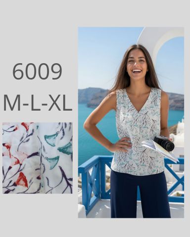 Mujer sonriente con blusa estampada frente al mar, fondo de montaña.