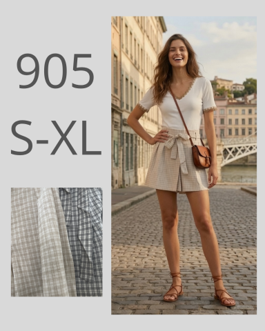 Mujer sonriente con blusa blanca y pantalones cortos claros, de pie en una calle.