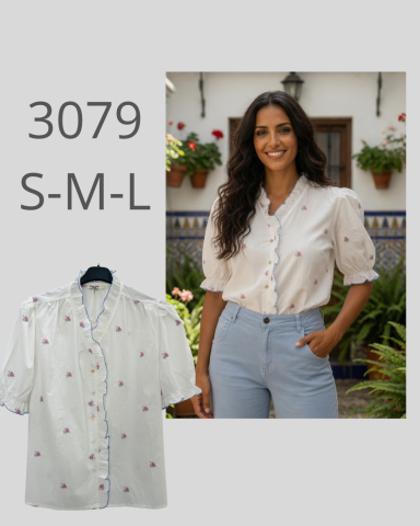 Mujer sonriente con blusa blanca y pantalones claros, fondo de casa con plantas.