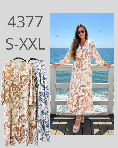 Mujer con vestido largo de estampado en tonos marrones frente al mar.