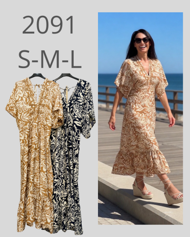 Vestido largo en tonos beige y negro, modelo 2091, con modelo caminando junto al mar.