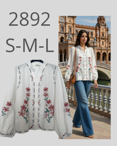 Blusa blanca con bordados florales y pantalones vaqueros, modelo posando en un puente.