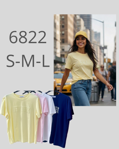 Mujer sonriente con camiseta amarilla y gorra, caminando por una calle de la ciudad.