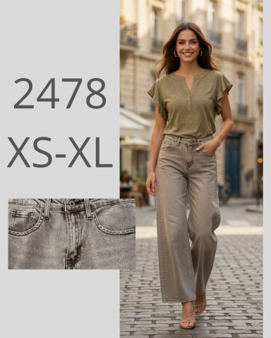 Mujer sonriente con blusa verde y pantalones beige, caminando por una calle empedrada.