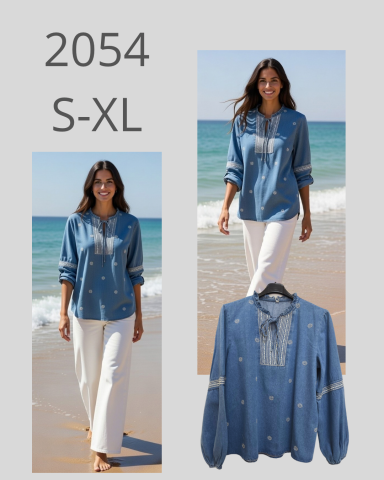 Mujer caminando en la playa con blusa azul y pantalones blancos. Modelo de ropa S-XL.
