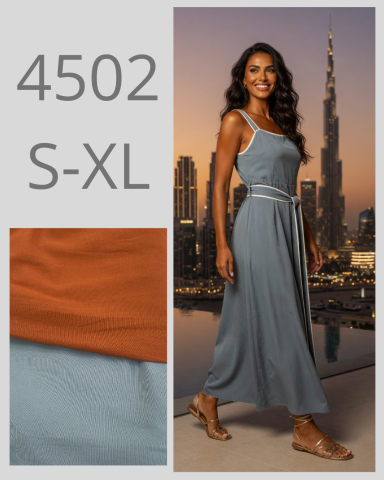 Mujer con vestido gris claro y cinturón, fondo de ciudad al atardecer.