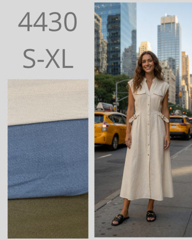 Mujer con vestido largo beige posando en una calle de ciudad con taxis amarillos.