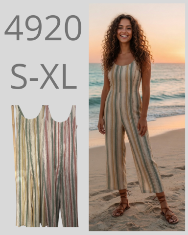Mujer sonriente con un mono de rayas, de pie en la playa al atardecer.