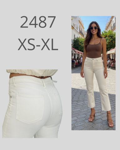 Mujer joven sonriente con pantalones blancos, camiseta marrón y sandalias en un entorno urbano.