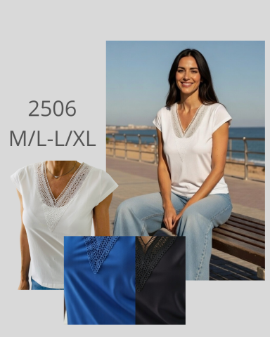 Mujer sentada junto al mar, luciendo una blusa blanca con detalles de encaje.