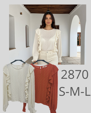 Mujer modelando blusas con volantes en colores crema y terracota, fondo arquitectónico.