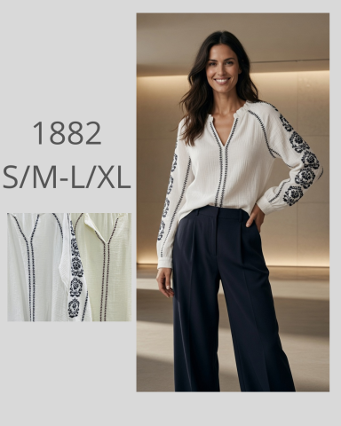 Mujer sonriente con blusa blanca y pantalones oscuros, pose elegante.