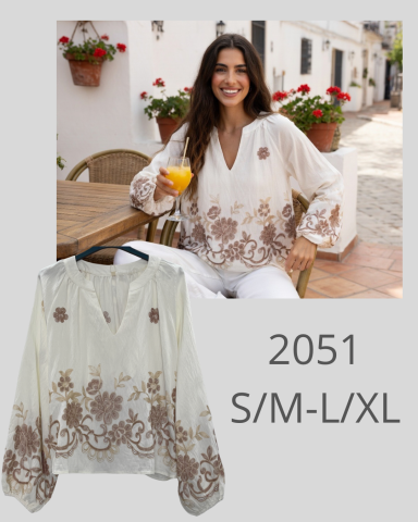 Mujer sonriente en blusa blanca con detalles marrones, sosteniendo un vaso de bebida.