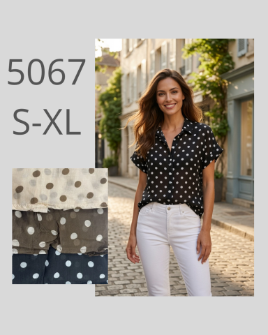 Mujer sonriente con blusa de lunares y pantalones blancos en una calle pintoresca.