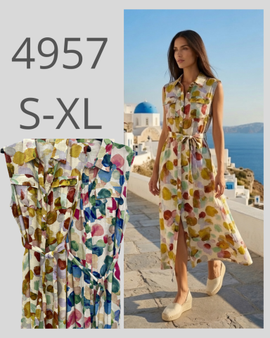 Mujer en vestido largo con estampado florido caminando por un camino junto al mar.
