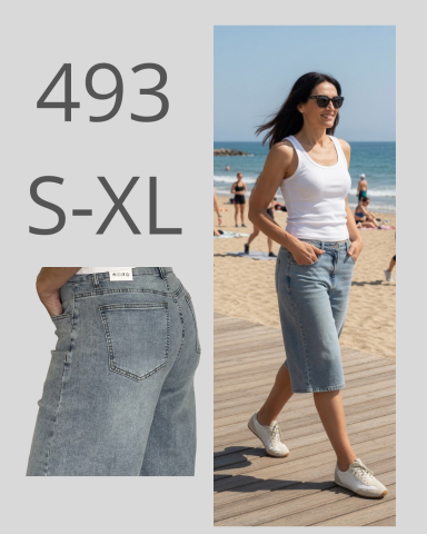 Mujer con pantalones cortos de mezclilla en la playa, luciendo una camiseta blanca.