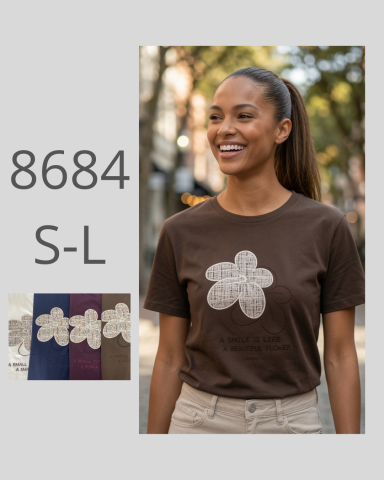 Mujer sonriente con camiseta marrón y diseño de flor en un entorno urbano.