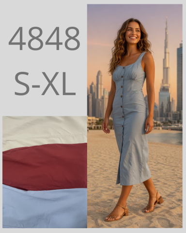 Mujer sonriente con vestido azul claro frente a edificios altos, junto a muestras de tela.