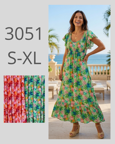Mujer sonriente con vestido largo floral frente al mar, opción de tallas S-XL.