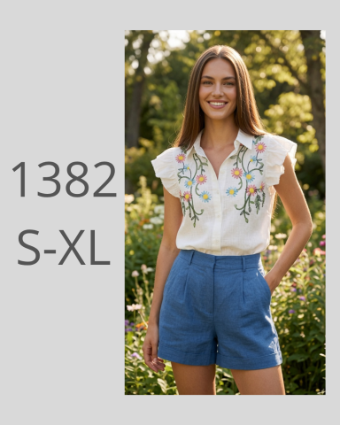 Mujer sonriente con blusa bordada y pantalones cortos en un entorno natural.