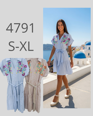 Mujer sonriente luciendo un vestido con bordados coloridos frente a un paisaje mediterráneo.