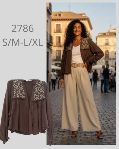 Mujer de pie con blusa marrón y pantalones amplios en un ambiente urbano.