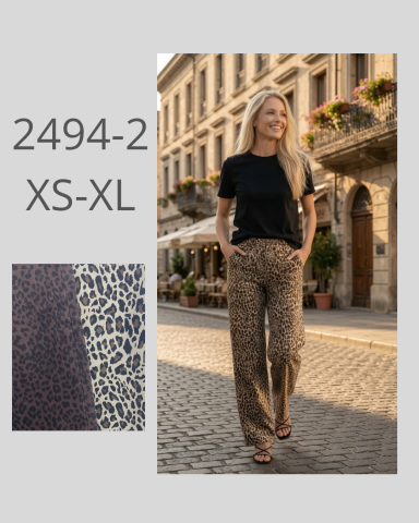 Mujer de pie en la calle con pantalones estampados y camiseta negra.