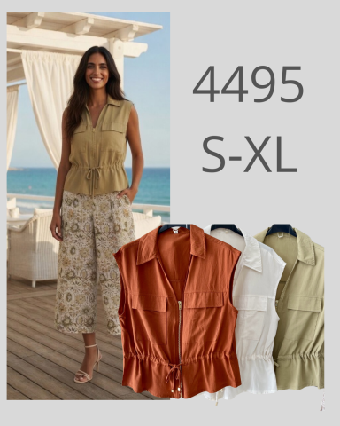 Mujer posando en un entorno costero, vistiendo blusa y pantalones con estampado floral.