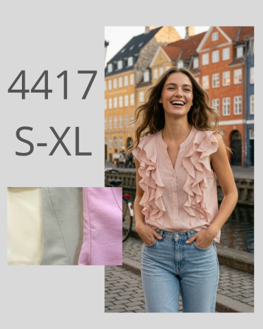 Mujer sonriente con blusa con volantes y jeans, fondo de casas coloridas junto al agua.