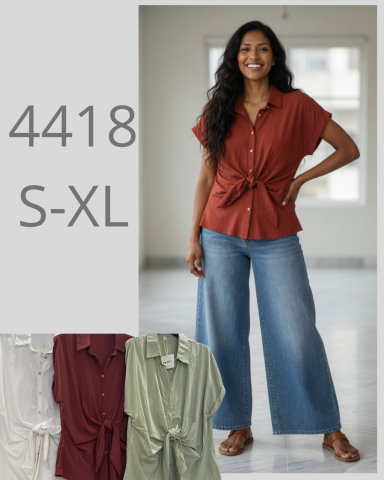 Mujer con blusa marrón y pantalones anchos, sonriendo frente a una pared clara.