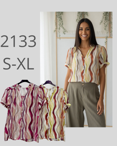 Mujer de pie con blusa de estampado colorido y pantalones. Tallas S-XL disponibles.