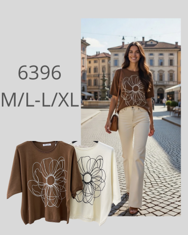 Mujer con camiseta marrón con diseño floral y pantalones claros, caminando por una plaza.