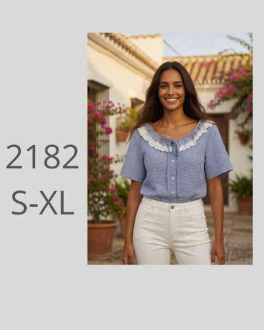 Mujer sonriente con blusa azul y pantalones blancos en un entorno floral.