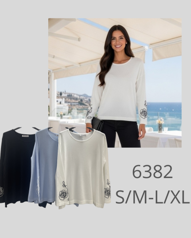 Mujer sonriente vistiendo camiseta de manga larga en un entorno costero, disponible en varios colores.