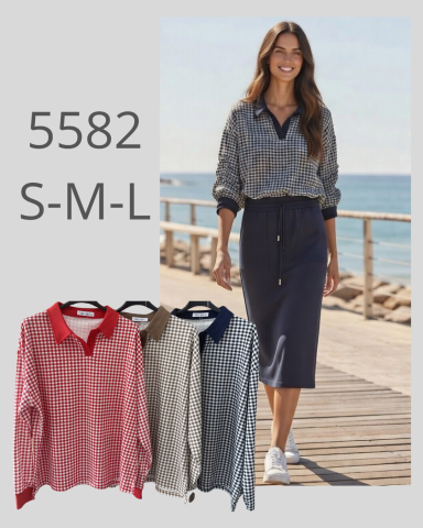 Modelo con camisa de moda y falda en un entorno al aire libre junto al mar.