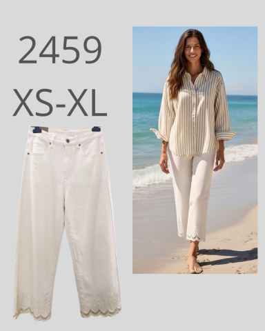 Mujer caminando por la playa con pantalones claros y camisa encima, en un día soleado.
