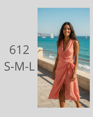 Mujer sonriente con un vestido coral frente al mar, paisaje soleado.