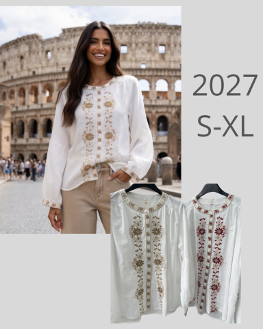 Mujer sonriente frente al Coliseo, vestida con blusa blanca decorada.