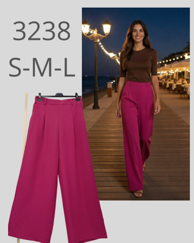 Mujer con pantalones fucsias y camiseta marrón caminando por un paseo iluminado.