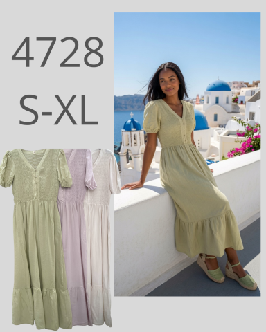 Mujer sentada en el borde de una terraza, vistiendo un vestido verde claro en Santorini.