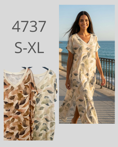 Mujer sonriente con vestido estampado de hojas, caminando junto al mar al atardecer.