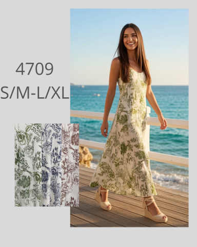 Mujer sonriente con vestido floral caminando junto al mar en un día soleado.