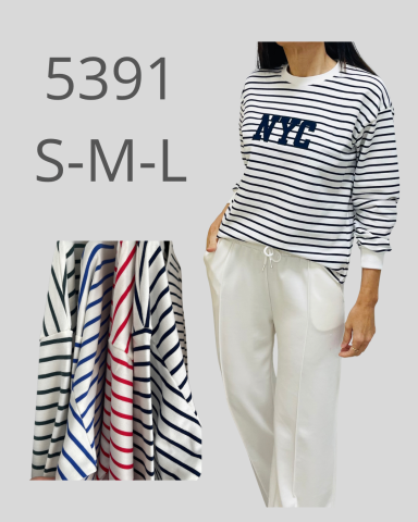 Una mujer viste una camiseta de rayas con la inscripción "NYC" y pantalones blancos.