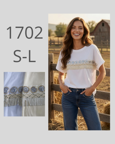Mujer sonriente con camiseta blanca y bordado, jeans, de pie junto a una cerca en un campo.