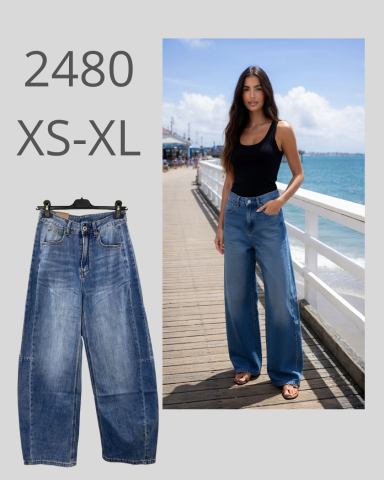 Vaqueros anchos de mezclilla en un entorno costero, modelo usa top negro.